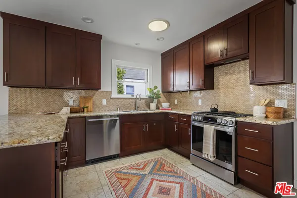 a kitchen with stainless steel appliances granite countertop wooden cabinets a stove top oven a sink and dishwasher