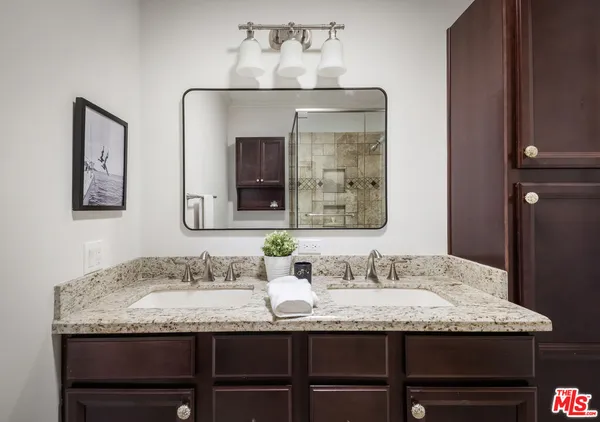 a bathroom with granite countertop double vanity sinks and a mirror