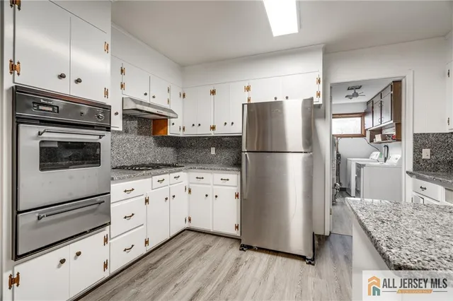 a kitchen with granite countertop white cabinets and stainless steel appliances