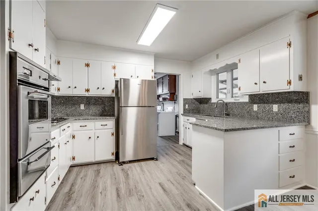 a kitchen with granite countertop a refrigerator stove and white cabinets