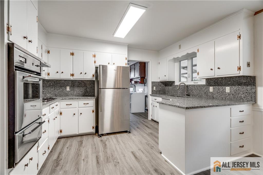 1474 Huron Road North Brunswick, NJ 08902 - Photo 7 of 16 a kitchen with granite countertop a refrigerator stove and white cabinets