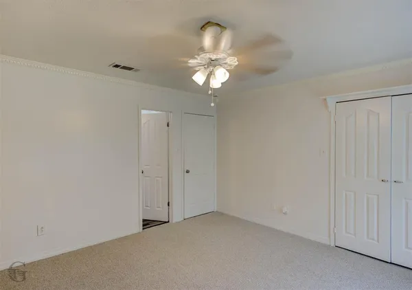a view of an empty room and chandelier fan