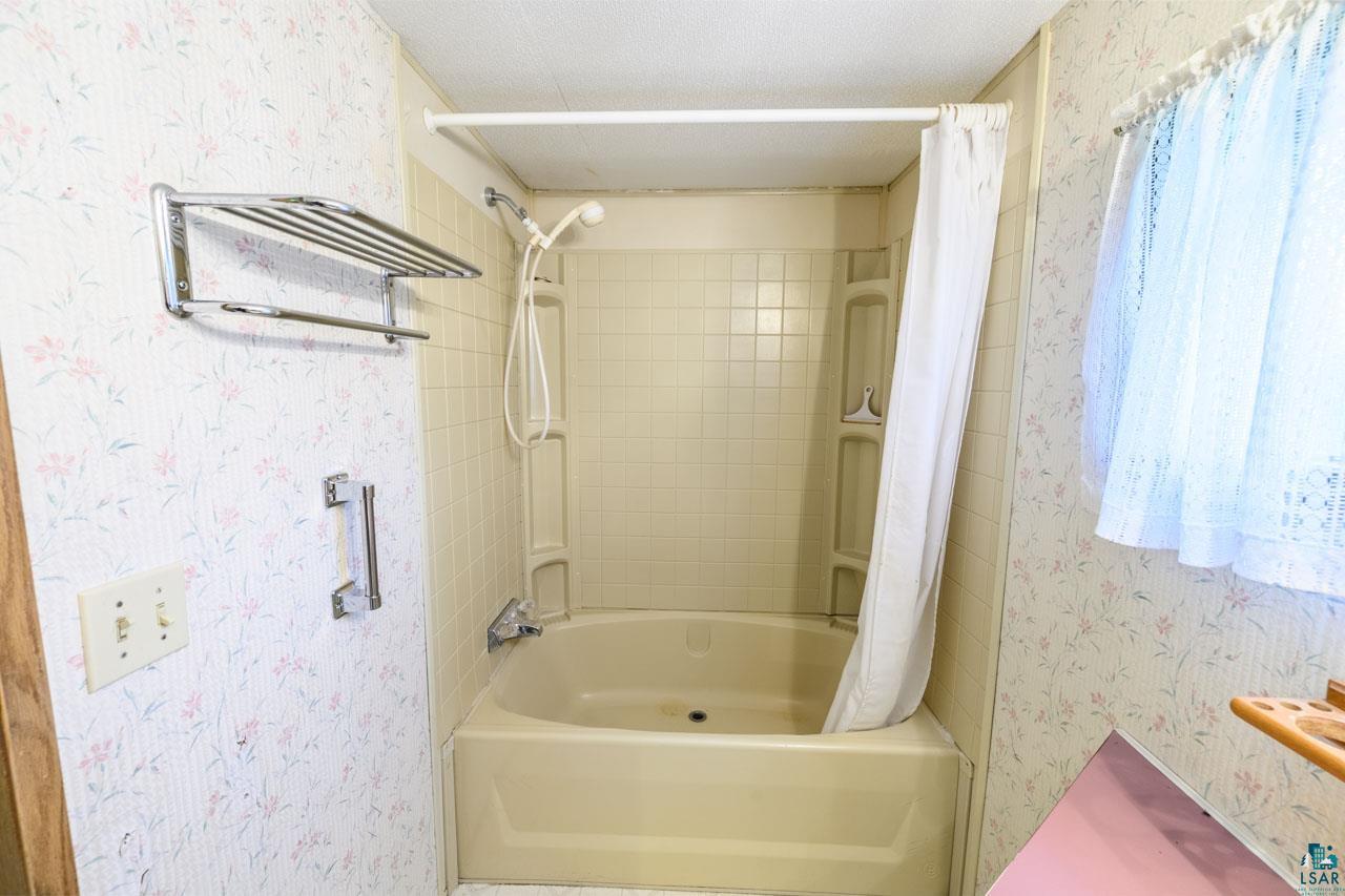 705 4th Street North Biwabik, MN 55708 - Photo 19 of 29 Built-in bathtub with integrated shower, accented by tiled surrounds and a handheld showerhead