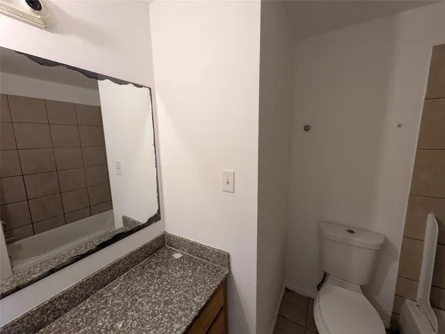 a bathroom with a granite countertop toilet and sink