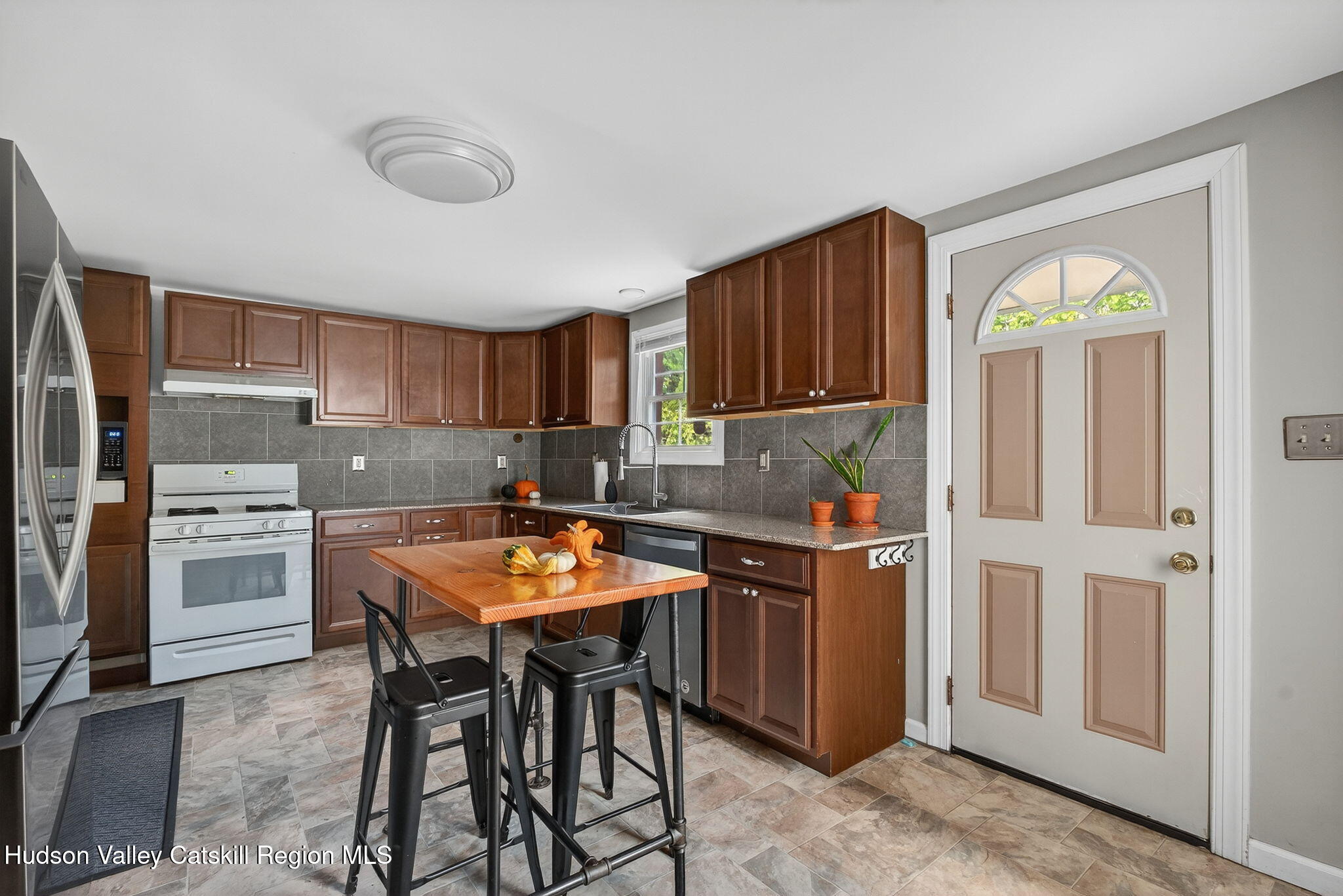 89 Spring Street Kingston, NY 12401 - Photo 5 of 24 a kitchen with stainless steel appliances granite countertop a stove top oven a refrigerator a sink a dining table and chairs with wooden floor