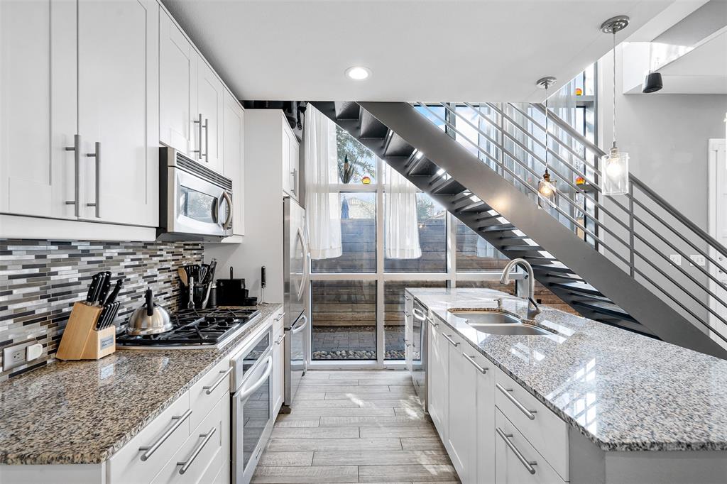 a large kitchen with granite countertop a sink and dishwasher a stove top oven with wooden floor