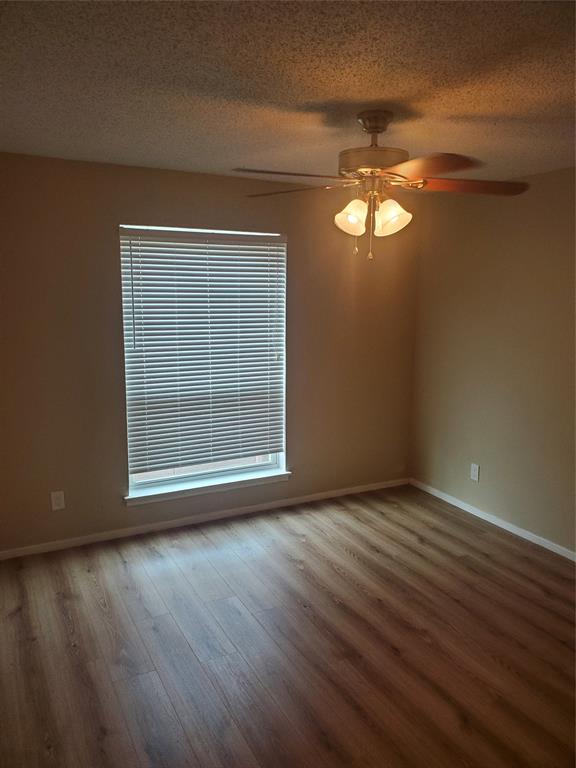 5532 Boca Raton Boulevard, Unit 290 Fort Worth, TX 76112 - Photo 12 of 16 Spacious room featuring wood-finish flooring, a window with zebra shades, and a ceiling fan