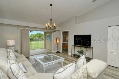 a living room with furniture a flat screen tv and a chandelier