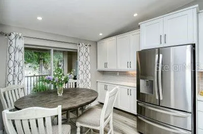 a kitchen with stainless steel appliances granite countertop a refrigerator a stove a dining table and chairs