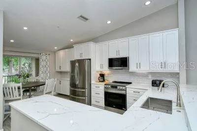 a kitchen with granite countertop a refrigerator stove and sink