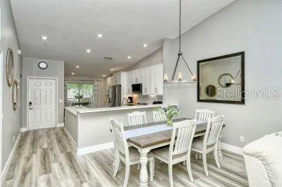 a kitchen with stainless steel appliances kitchen island granite countertop a dining table chairs and white cabinets