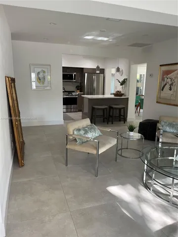 a dining hall with stainless steel appliances kitchen island granite countertop a refrigerator a sink a dining table and chairs with wooden floor