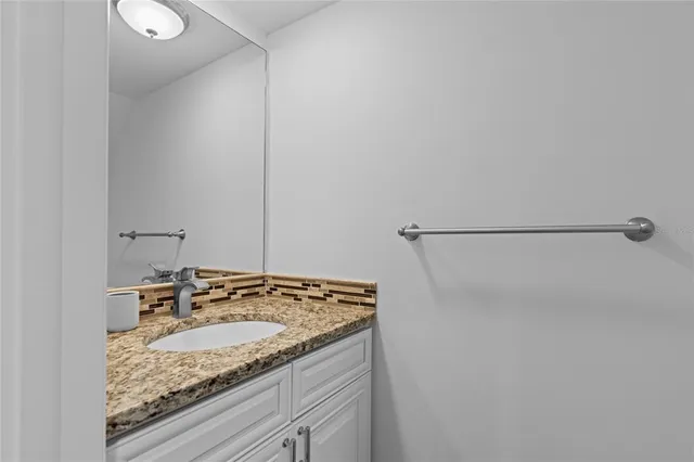 a bathroom with a granite countertop sink and a mirror