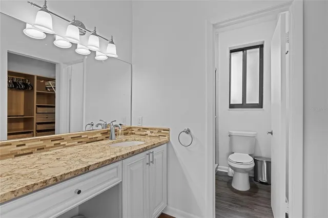 a bathroom with a granite countertop sink a toilet and mirror