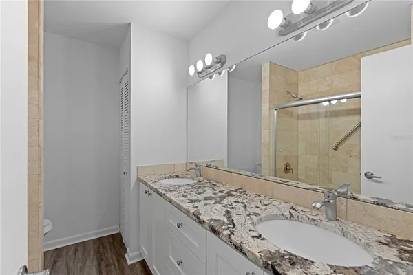 a bathroom with a granite countertop sink a large mirror and a shower