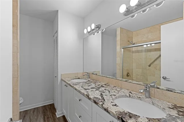 a bathroom with a granite countertop sink a large mirror and a shower