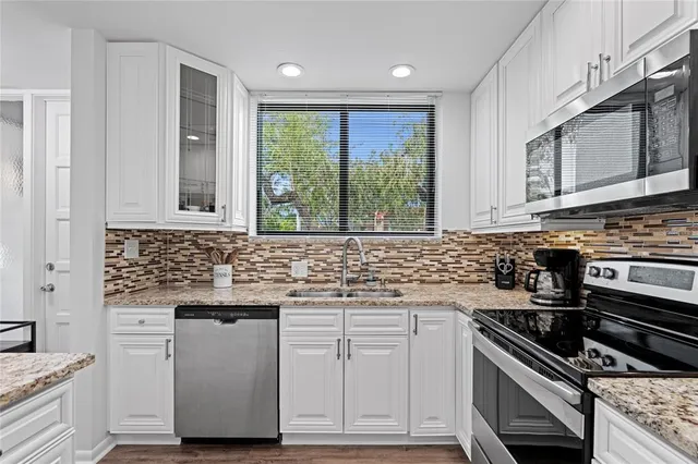 a kitchen with stainless steel appliances white cabinets and a stove top oven