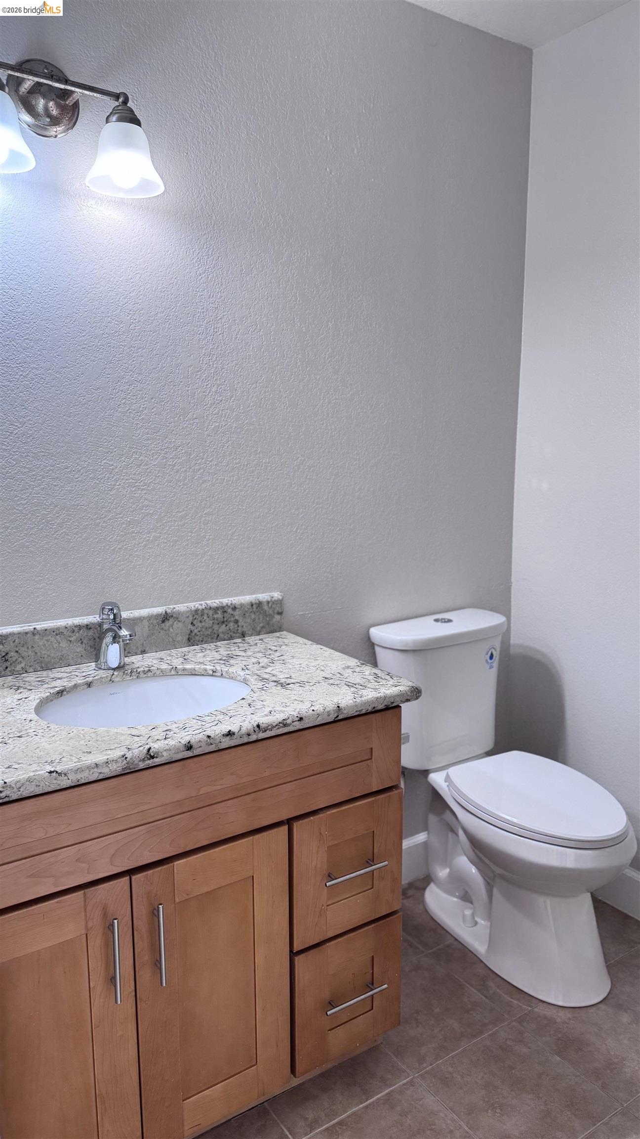 23 Raintree Court, Unit 15 Hayward, CA 94544 - Photo 9 of 16 Bathroom featuring vanity, dark tile patterned flooring, and a textured wall