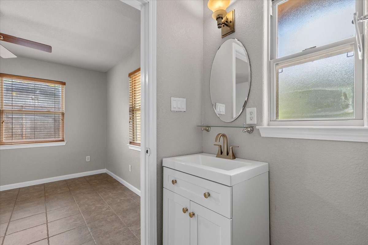 7604 Robalo Road Austin, TX 78757 - Photo 21 of 36 A well-appointed bathroom vanity with a clean white sink and modern fixtures offers convenient access to an adjacent room.