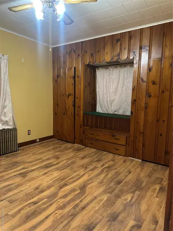 en empty room with wooden floor and fan