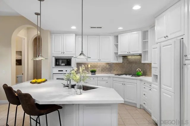 a kitchen with stainless steel appliances kitchen island granite countertop a white refrigerator a sink a stove a dining table and chairs