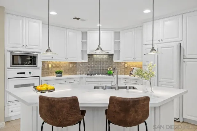 a kitchen with stainless steel appliances a dining table chairs and a refrigerator