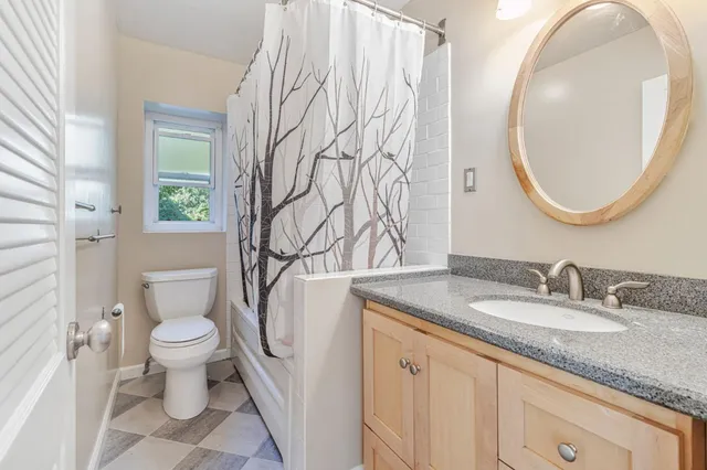 a bathroom with a granite countertop toilet sink and mirror