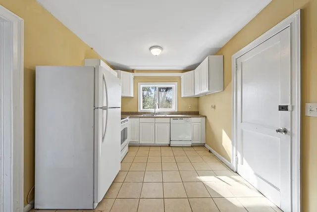 a large white kitchen with cabinets a sink a counter top space and stainless steel appliances