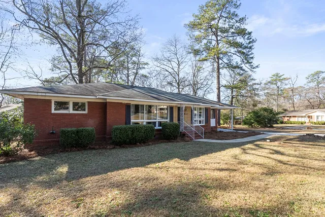 a front view of a house with a garden and trees