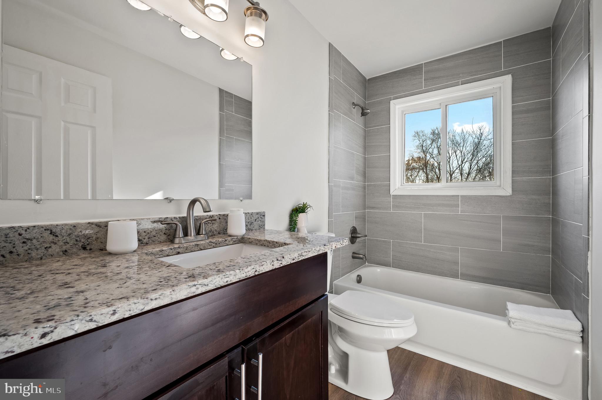 200 Timber Grove Road Reisterstown, MD 21136 - Photo 12 of 30 a bathroom with a granite countertop sink a toilet a mirror and bathtub