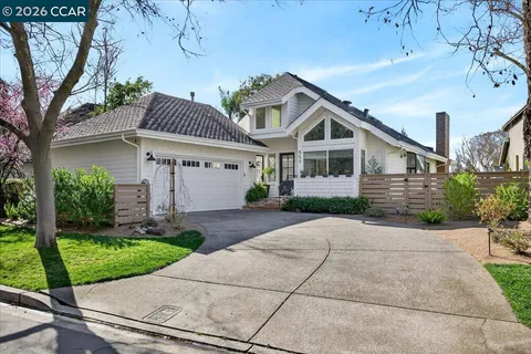 a view of a white house with a small yard and large tree