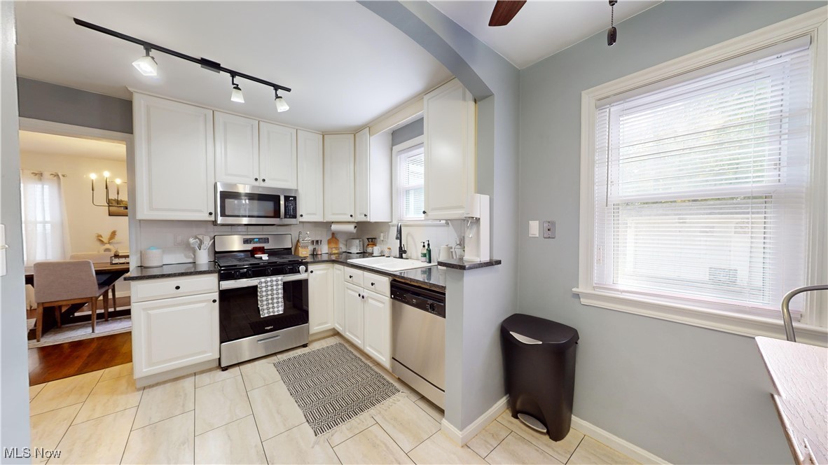 Kitchen featuring appliances with stainless steel finishes, plenty of natural light, sink, and white cabinetry
