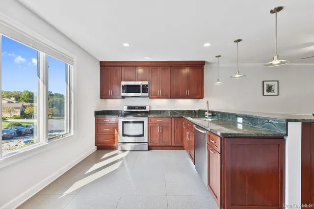 a large kitchen with stainless steel appliances granite countertop a stove a sink and a refrigerator