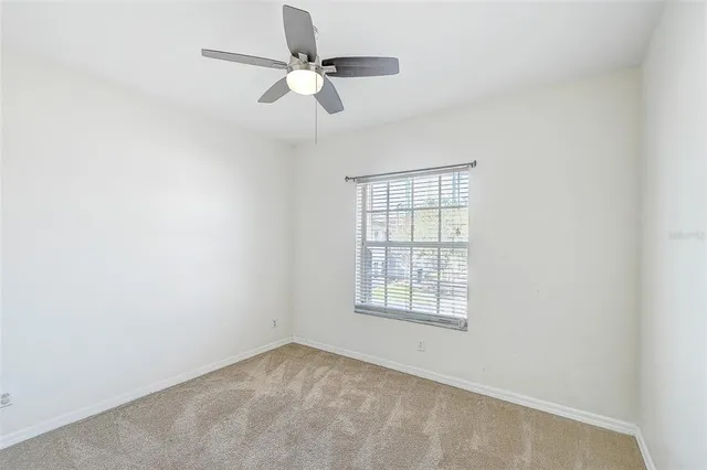 an empty room with a window and a fan