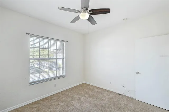 an empty room with windows and fan