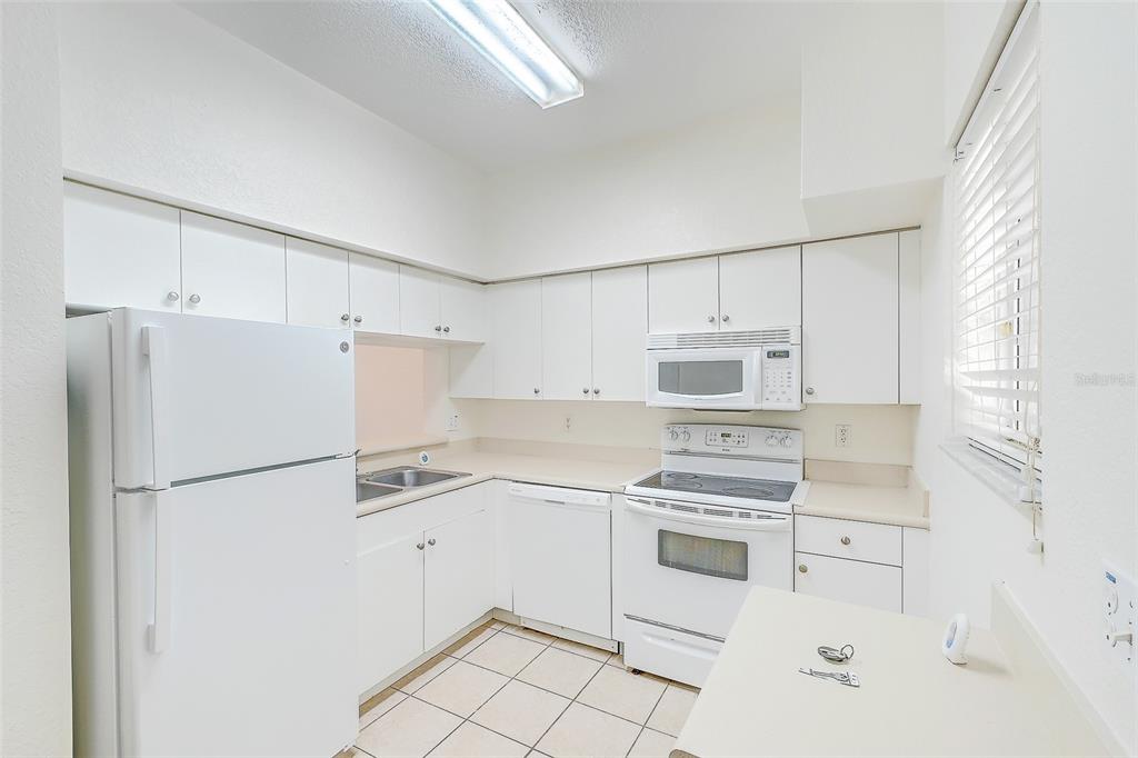 8358 Bernwood Cove Loop, Unit 708 Fort Myers, FL 33966 - Photo 27 of 32 a kitchen with white cabinets and white appliances