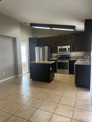 a kitchen with kitchen island granite countertop a stove a sink and a refrigerator