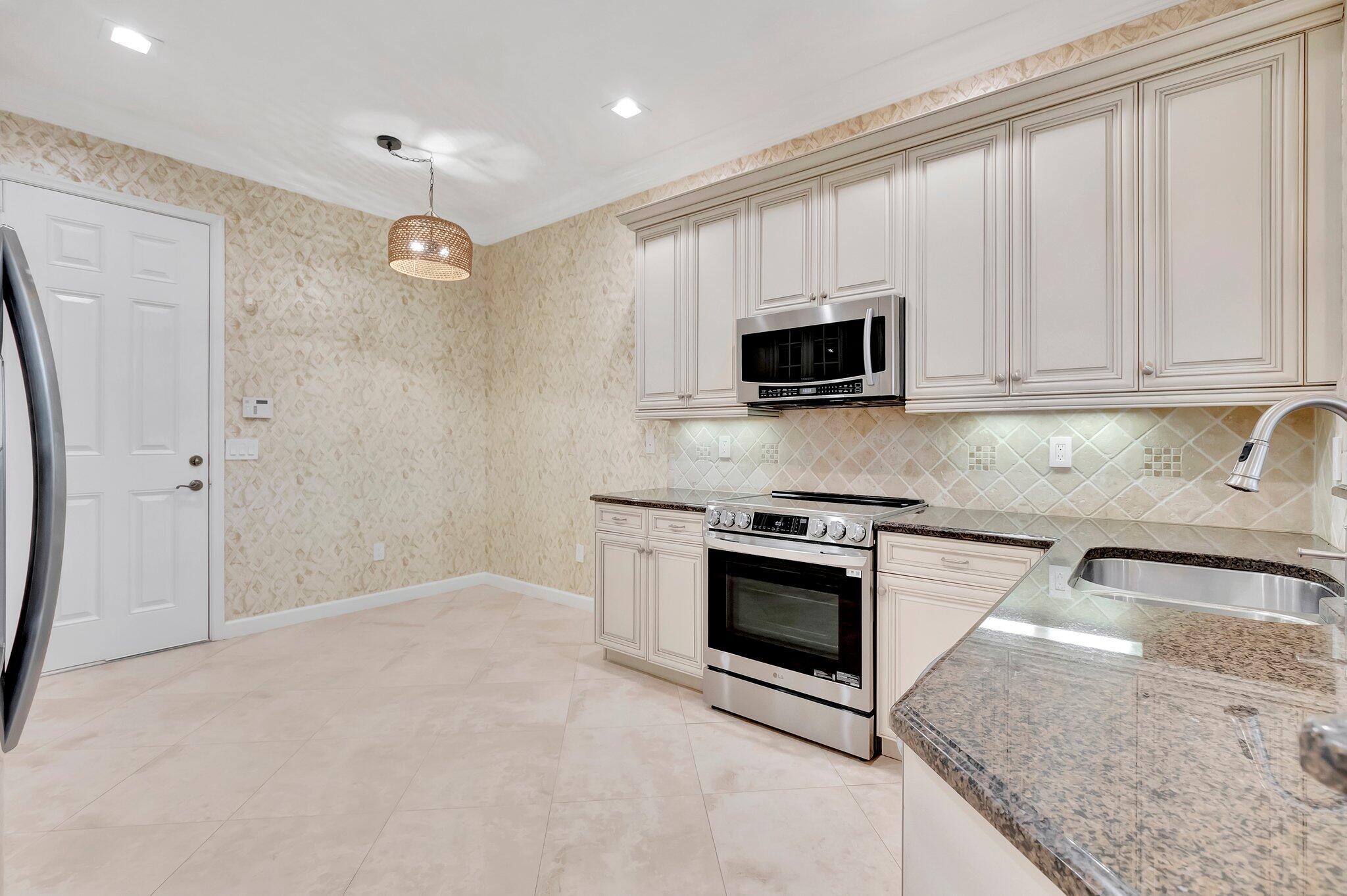 100 West Prive Circle Delray Beach, FL 33445 - Photo 15 of 43 a kitchen with granite countertop a stove a sink and a microwave