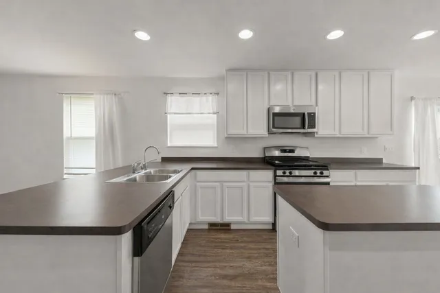 a kitchen with kitchen island granite countertop a sink and stainless steel appliances