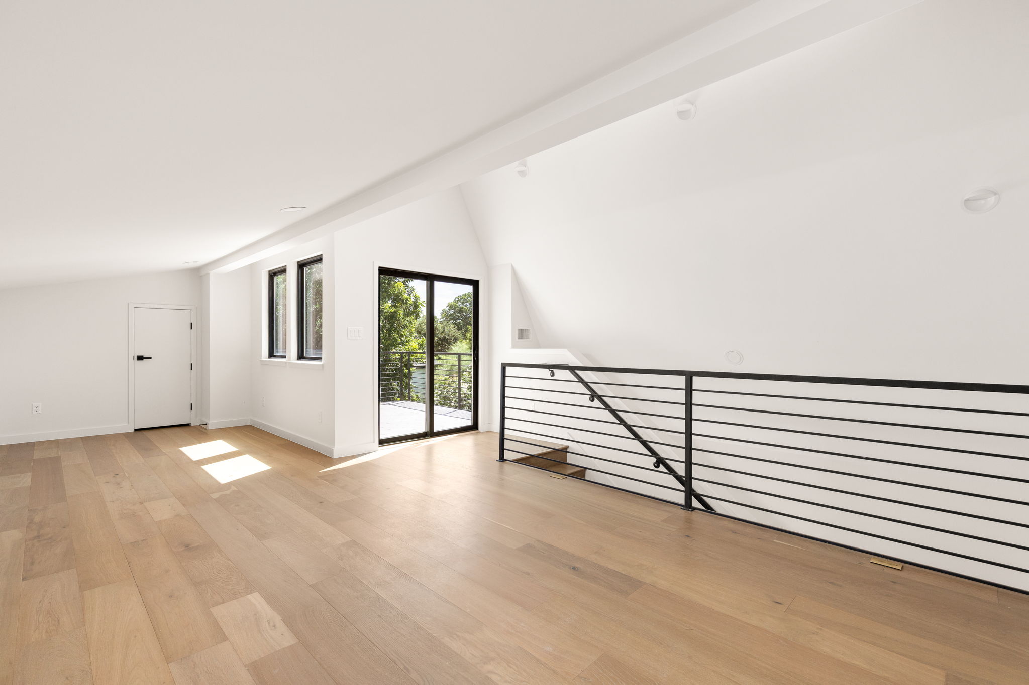 2717 Lyons Road, Unit 1 Austin, TX 78702 - Photo 30 of 40 An airy, sun-filled loft space featuring light hardwood flooring and modern railing, opening to a tranquil balcony.