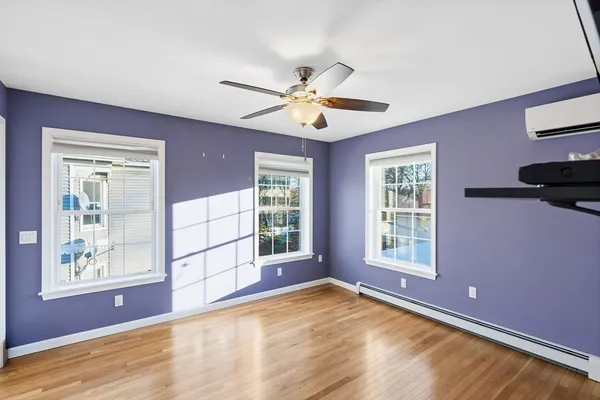a view of an empty room with a window and wooden floor