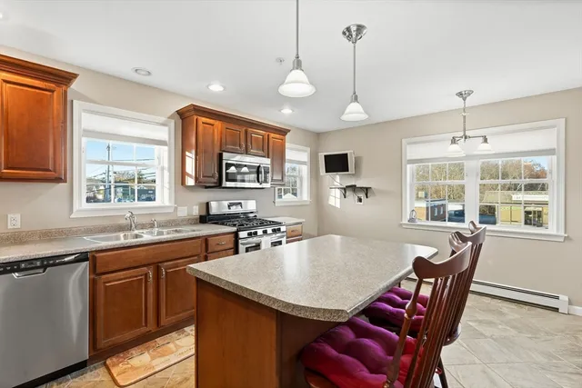a open kitchen with stainless steel appliances granite countertop a stove a sink a microwave a dining table and chairs