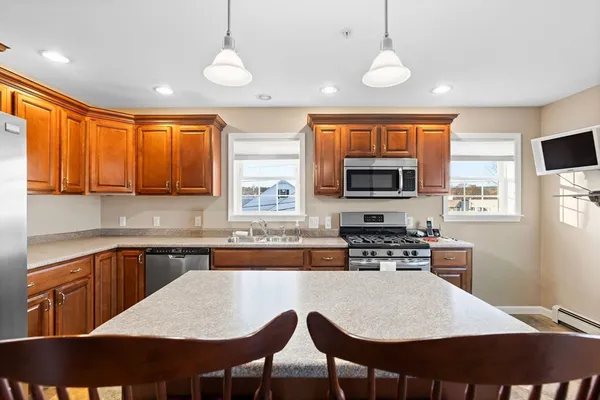 a kitchen with stainless steel appliances granite countertop a stove a sink a microwave a dining table and chairs with wooden floor