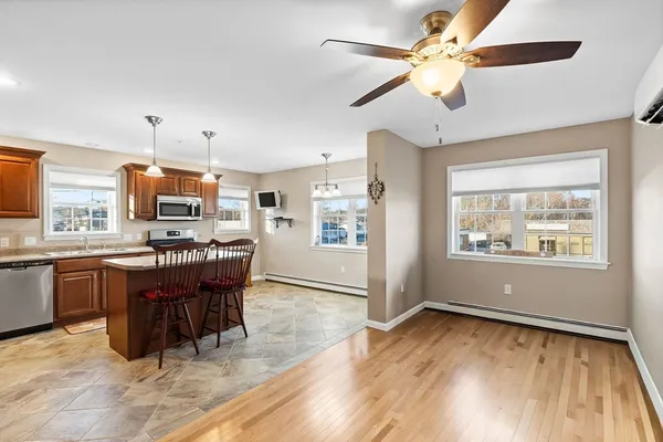 a kitchen with stainless steel appliances granite countertop a stove top oven a refrigerator a dining table and chairs with wooden floor