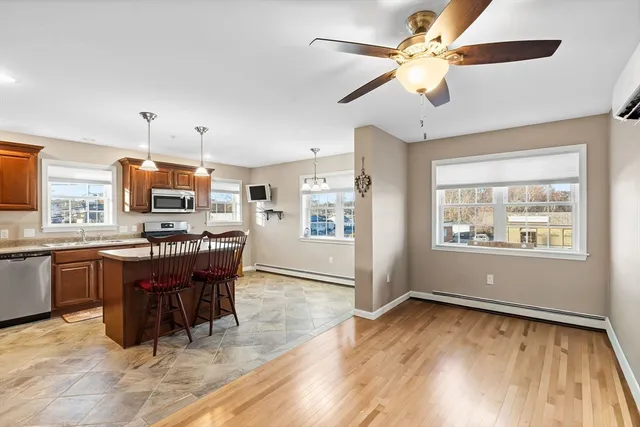 a kitchen with stainless steel appliances granite countertop a stove top oven a refrigerator a dining table and chairs with wooden floor