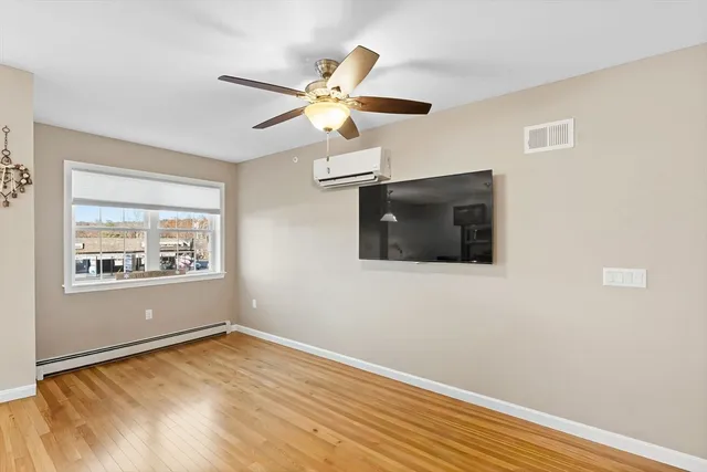 a view of an empty room with window and wooden floor