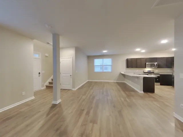 a view of kitchen and empty room with wooden floor