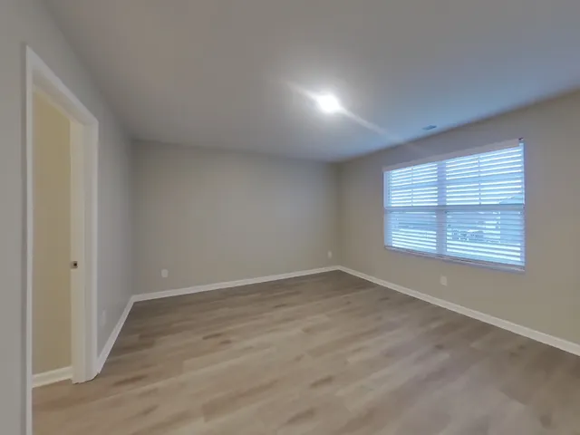 an empty room with wooden floor and windows