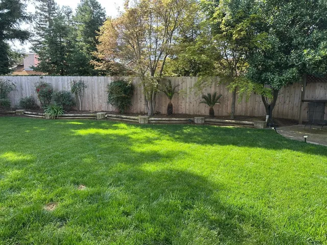 a backyard of a house with table and chairs and wooden fence