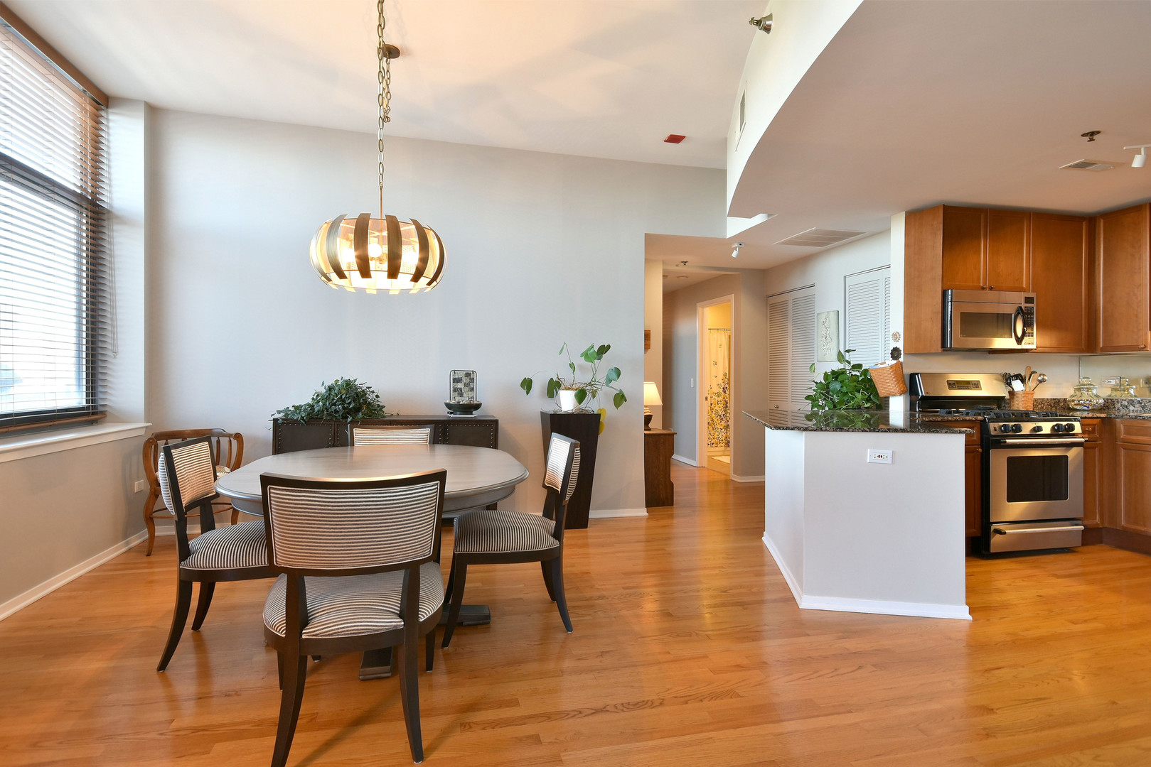1201 West Adams Street, Unit 411 Chicago, IL 60607 - Photo 13 of 40 a kitchen with stainless steel appliances granite countertop a stove top oven a sink dishwasher a dining table and chairs with wooden floor